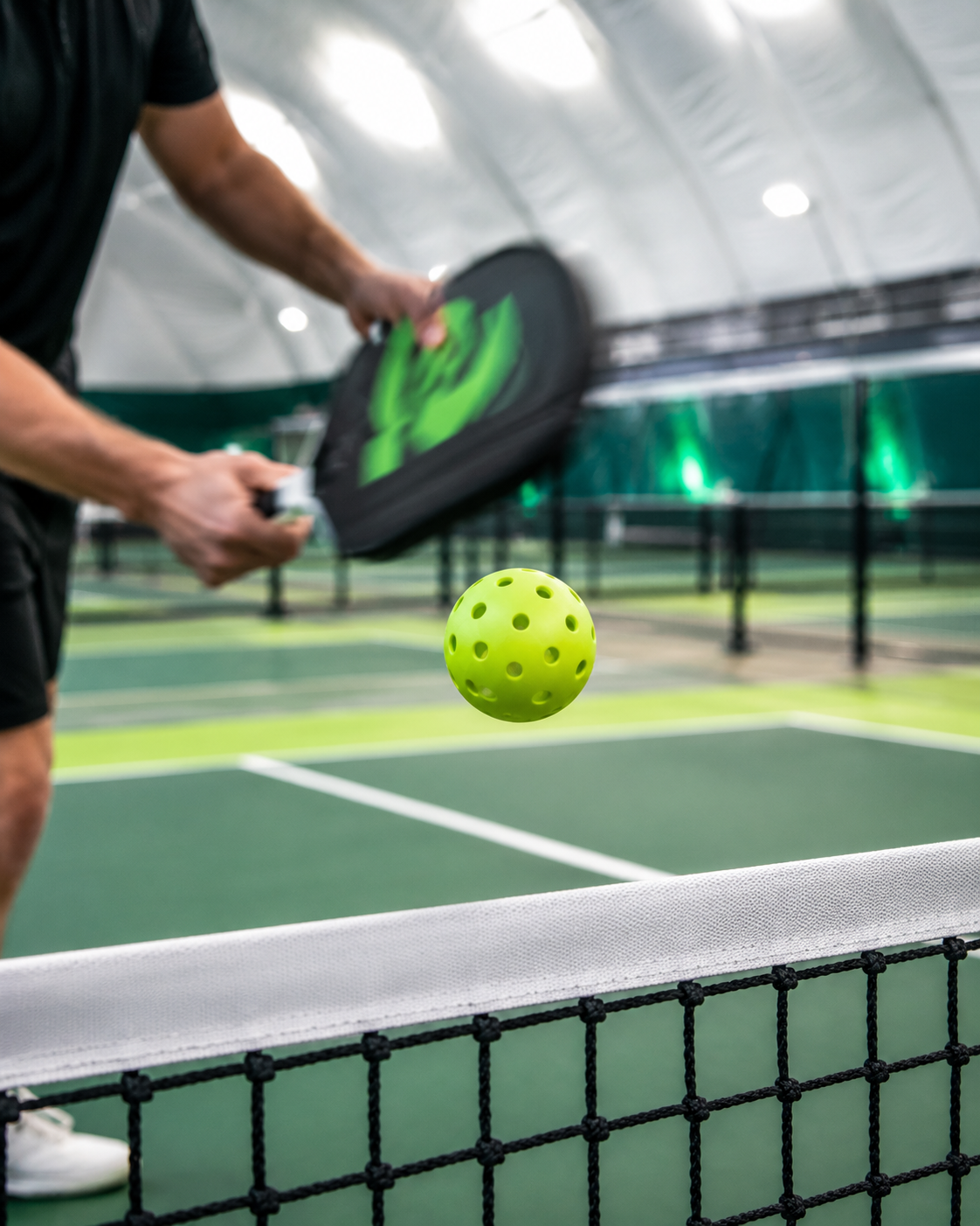 Pickleball player hitting a ball over the net inside an indoor sports dome, architectural rendering